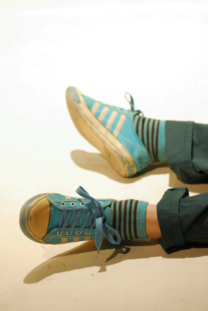 Baskets d'homme bleues avec des chaussettes rayés bleu et marron.