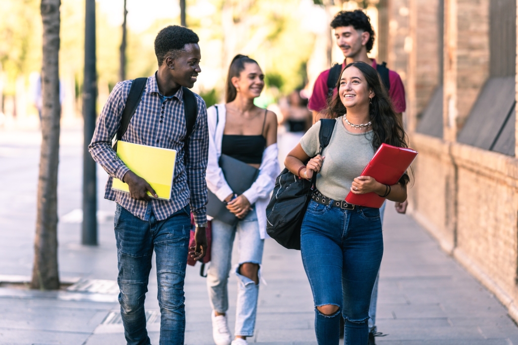 Quatre étudiants souriants marchent dans la rue.