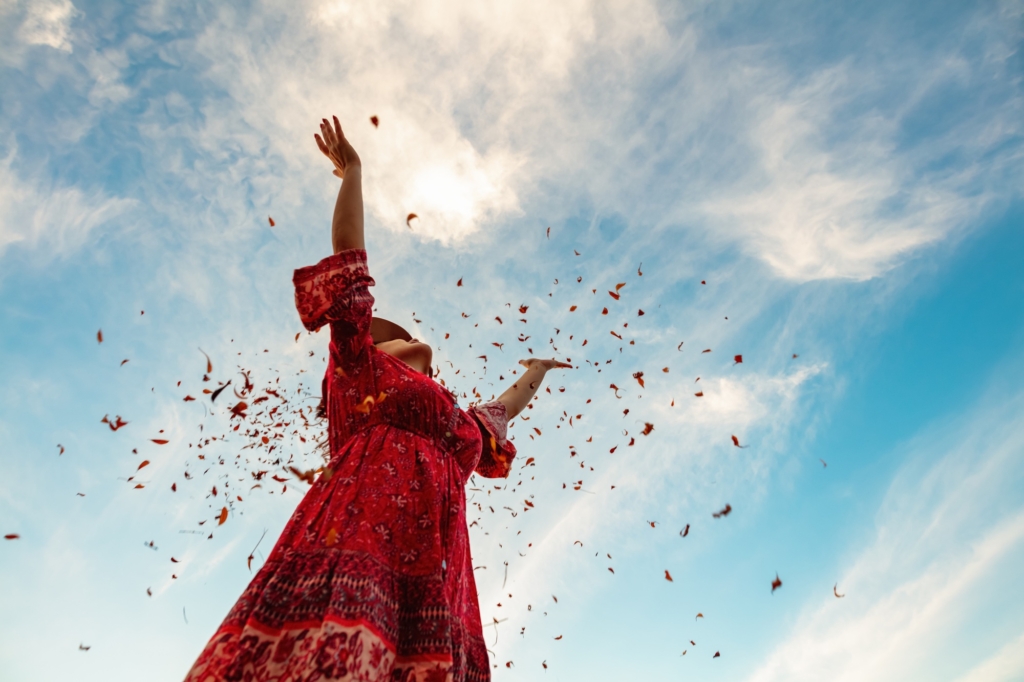 Jeune femme vue d'en bas qui jette des confettis en l'air.